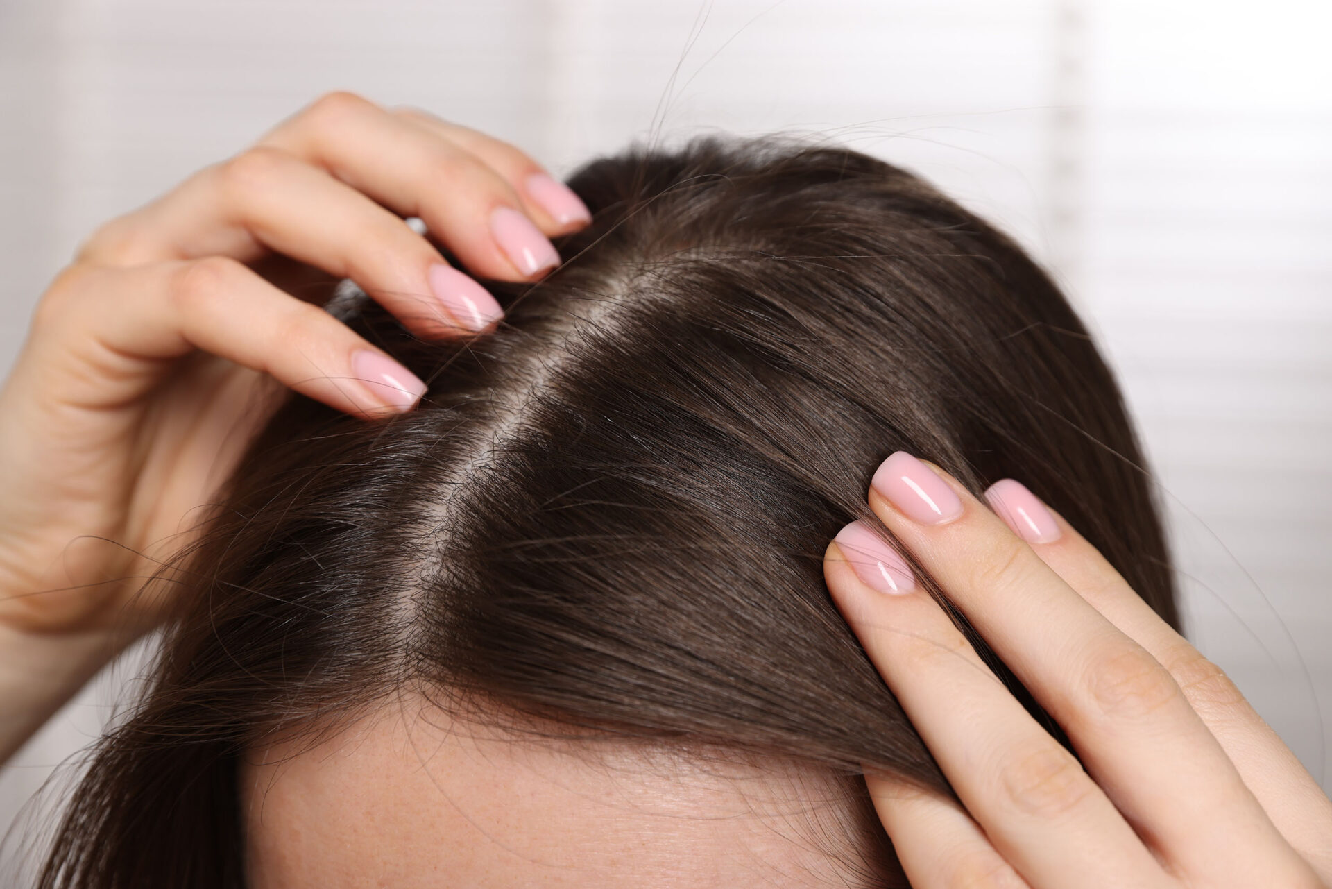 A woman examining her healthy scalp after a head spa treatment.