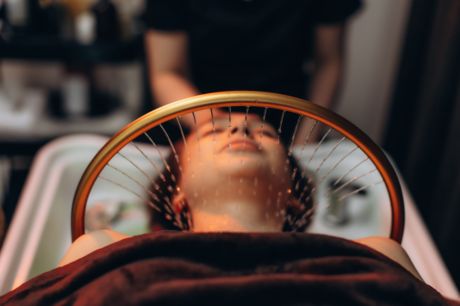 A woman receiving a head spa service to experience scalp treatment benefits