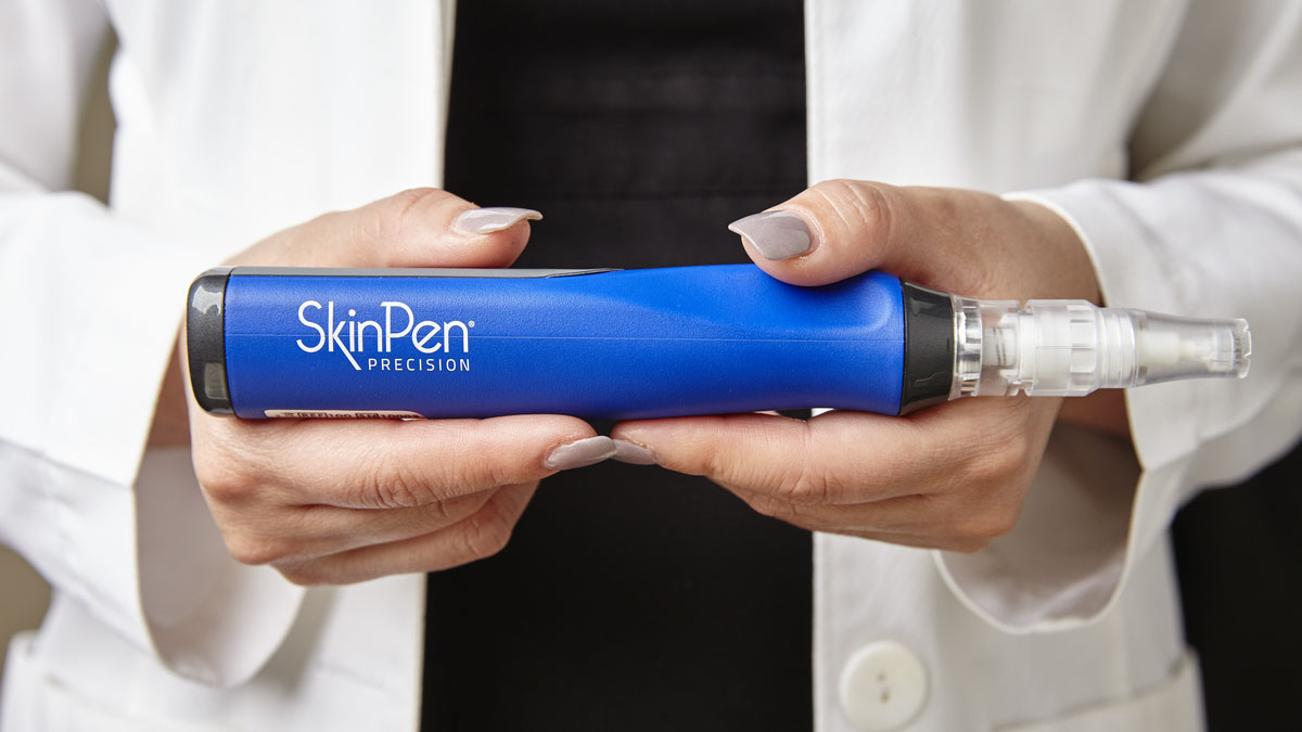 A close up of an esthetician's hands holding the SkinPen microneedling device.